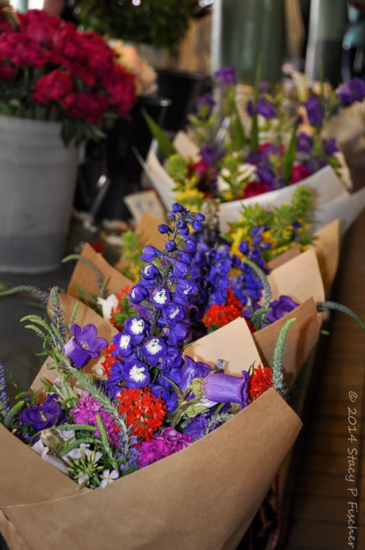 Bunches of brightly colored flowers bundled in paper cones waiting to be sold.