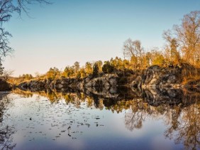 Looking westward down the length of the lake, with the reflection of the trees and bedrock bluffs in the blue water.