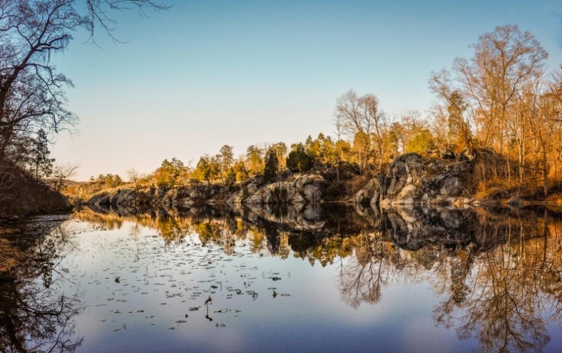 Looking westward down the length of Black Pond, with the reflection of the trees and bedrock bluffs in the blue water.