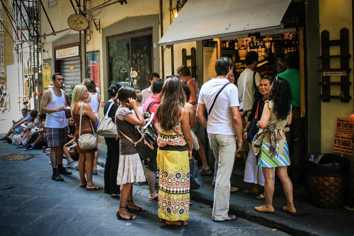 Patrons crowd around the walk-up window to order fresh panini and wine, and then sit on the curb to eat.