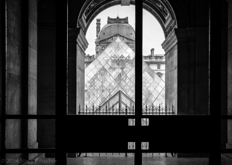 The top of the Pyramid is framed through an archway, with a portion of the Richelieu Pavillion visible through its glass.