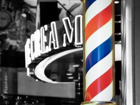 Red, white, and blue striped barber pole against black and white interior background
