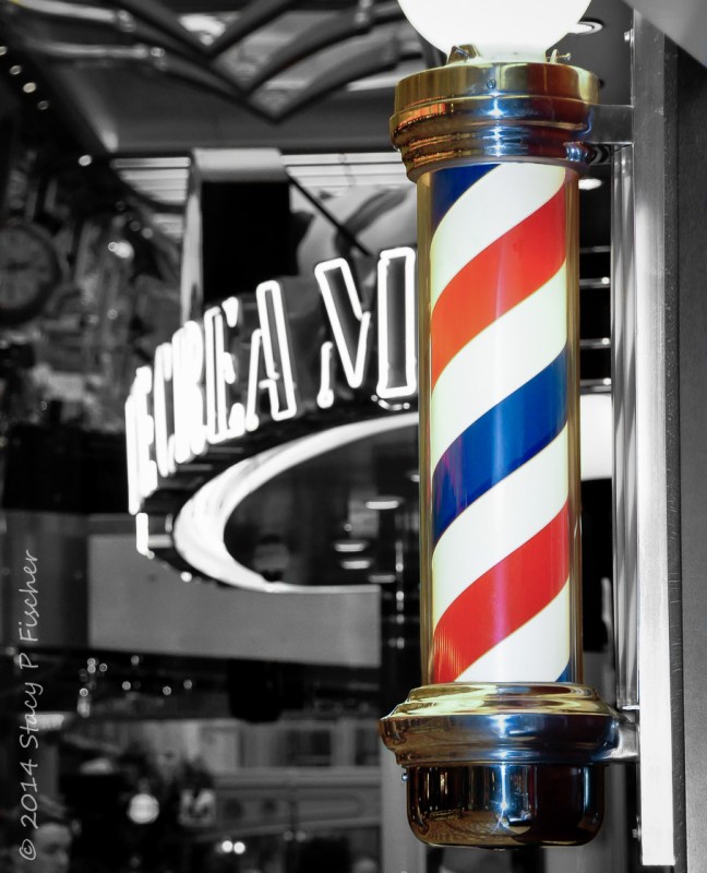Red, white, and blue striped barber pole against black and white interior background