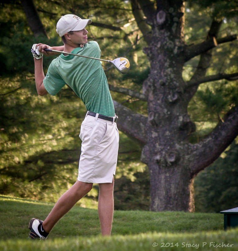 Golfer in final stance after teeing off.