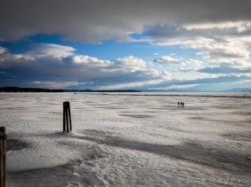 People walking on the frozen surface of Lake Champlain all the way out to the jetty and the lighthouse.