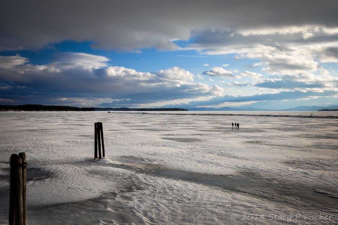People walking on the frozen surface of Lake Champlain all the way out to the jetty and the lighthouse.