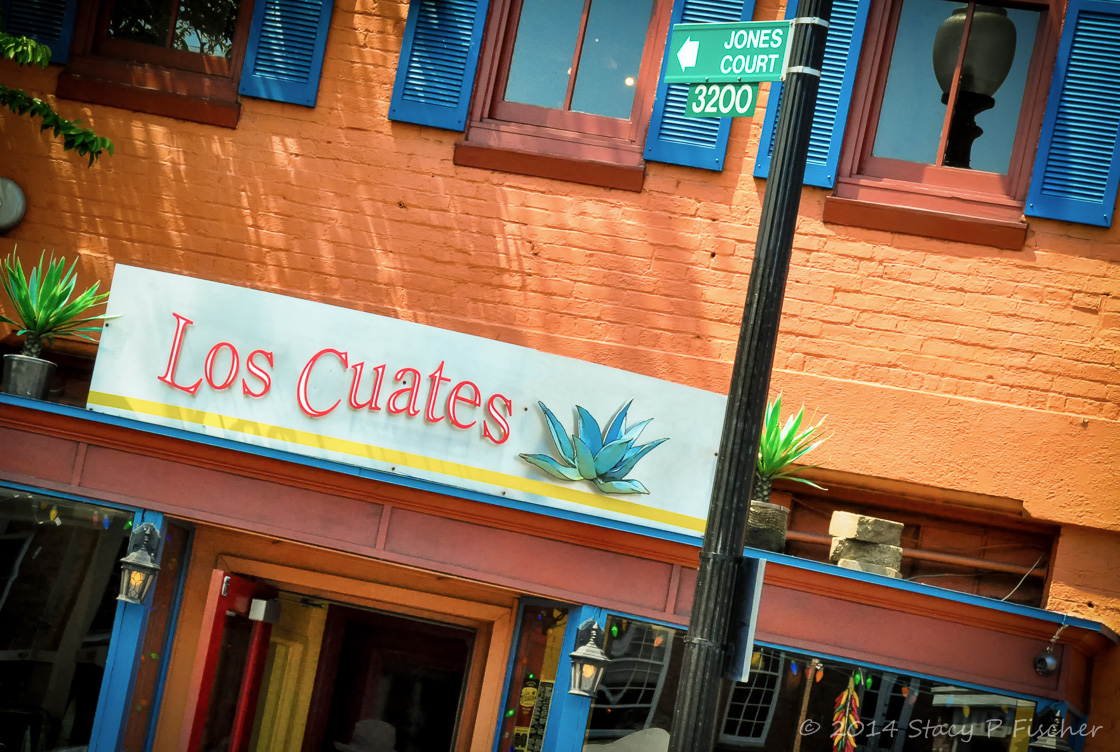 Orange brick, bright blue shutters, red and orange woodworking of Los Cuates Mexican Restaurant.