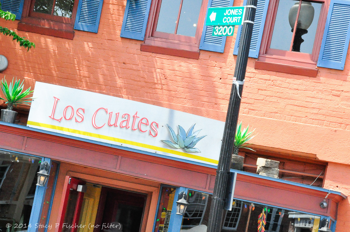 Orange brick, bright blue shutters, red and orange woodworking of Los Cuates Mexican Restaurant.