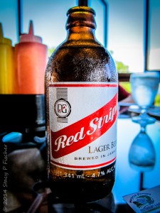 A bottle of Red Stripe covered in condensation, sitting on a tabletop.