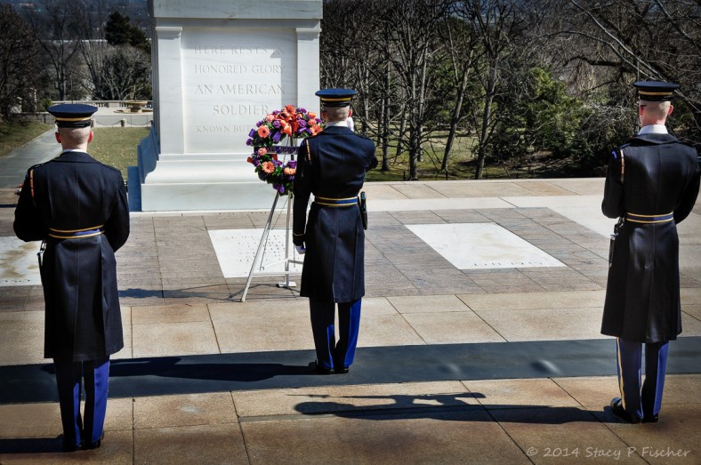 Three Honor Guards face and salute the tombs of the unknown soldiers.