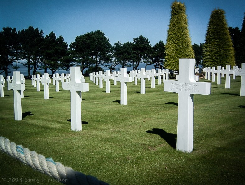 The white crosses aligned in rows against deep green grass and deep blue ocean. 