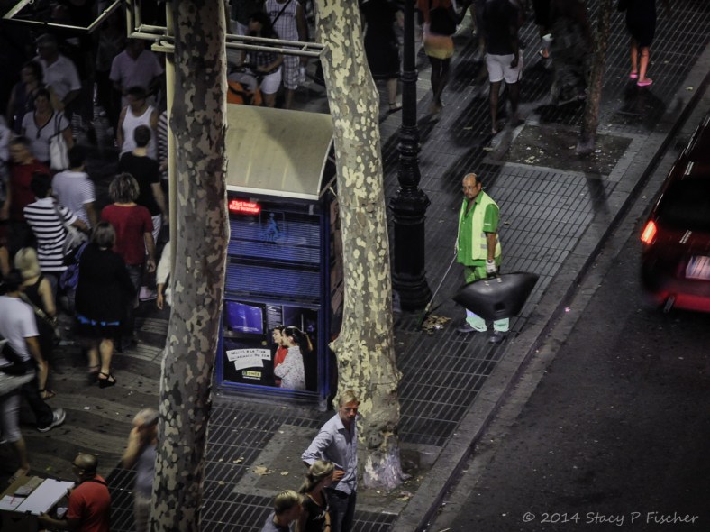  A lone trashman goes unnoticed by nighttime revelers on Barcelona's Las Ramblas.
