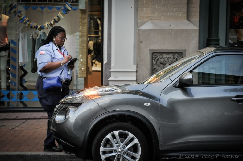 Traffic cop writes a parking ticket for a shiny new car.