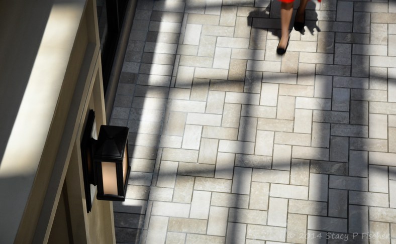 Light through skylights creates shadow grid on white herringbone-patterned flooring 