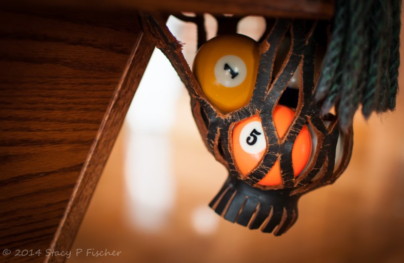 Orange and yellow pool balls inside an open-weave leather pool table pocket