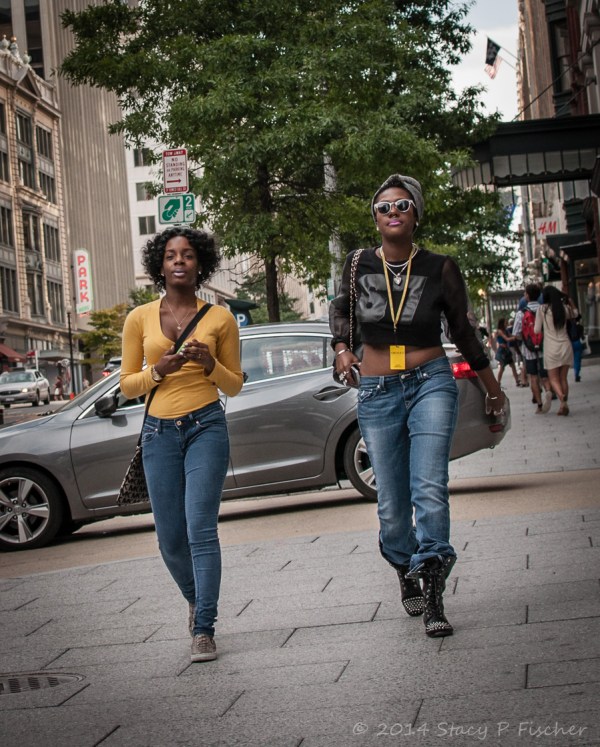 Two woman walking side-by-side on sidewalk, both wearing yellow