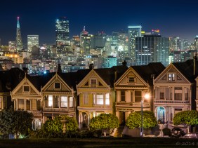 Painted Ladies of San Francisco at night glow against the backdrop of the sparkling San Francisco skyline.