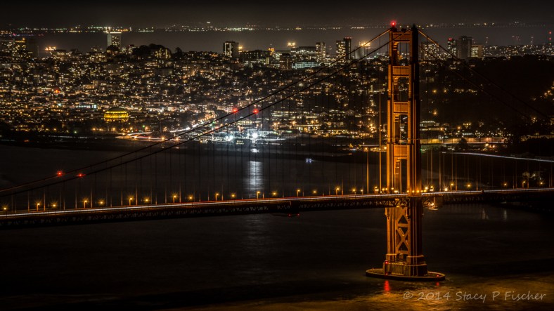 Golden Gate south tower at night, with city lights of San Francisco in the background