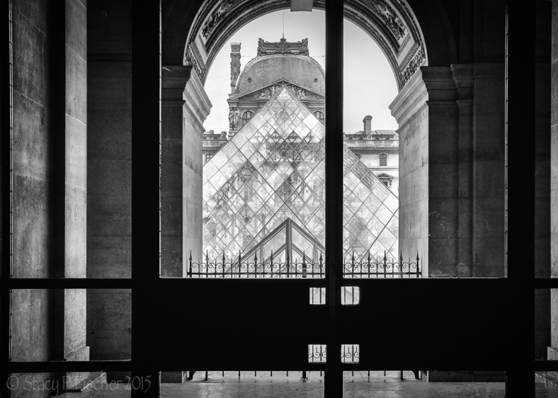 Louvre Pyramid viewed through an alcoved archway.