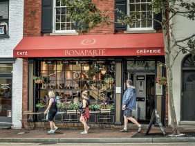 Three pedestrians walk past Cafe Bonaparte, Georgetown, Washington, DC