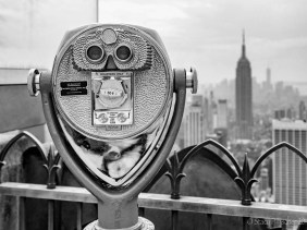 Binocular viewer atop Top of the Rock with Empire State Building in the background.