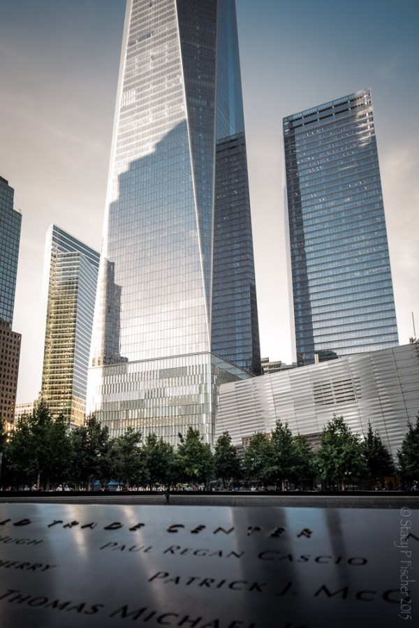Looking across inscribed names on bronze plate of South Tower reflecting pool to One World Trade Center.