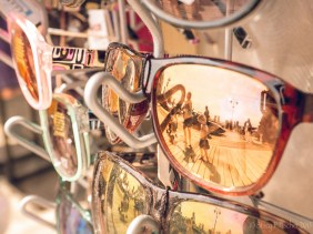 Sunglasses in stand reflecting summer activity on boardwalk