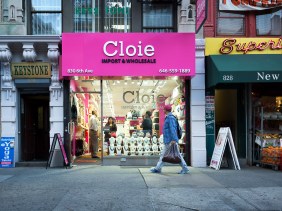A gentleman in a pink baseball cap walks past a pink storefront in New York City