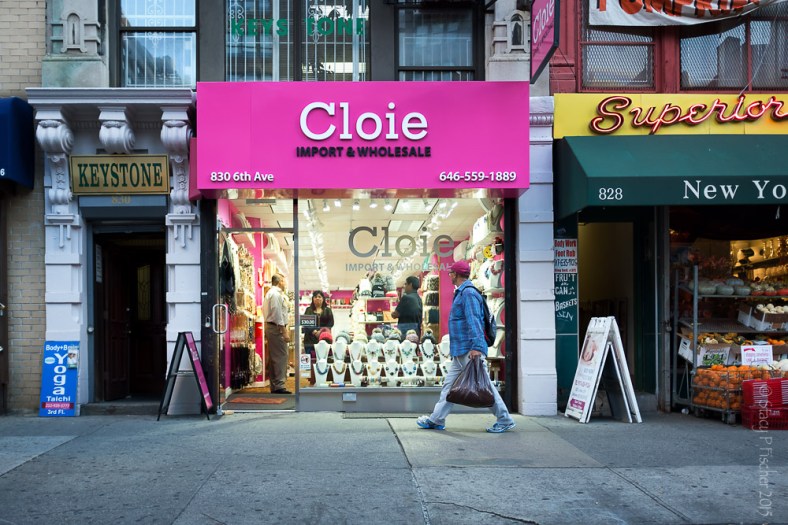 A gentleman in a pink baseball cap walks past a pink storefront in New York City