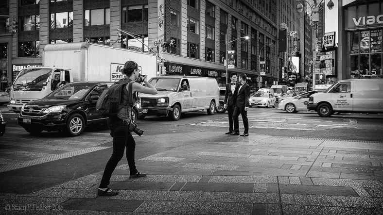 Photographer in Times Square takes photos of two tuxedoed young men